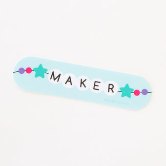 A sticker with a light blue background featuring the word 'MAKER' in friendship bracelet bead letters, surrounded by colorful star beads.