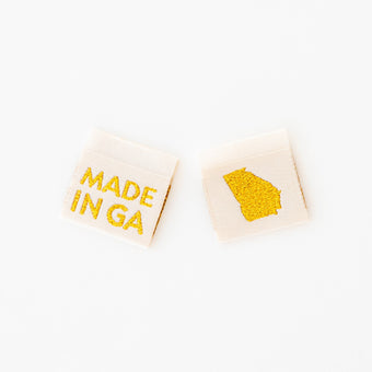 Woven sew-in labels by Sarah Hearts with 'MADE IN GA' text and a map of Georgia in metallic gold on a cream background