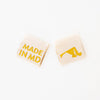woven sew in labels by Sarah Hearts with 'MADE IN MD' text and an outline of the state of Maryland in gold metallic thread on a white background.